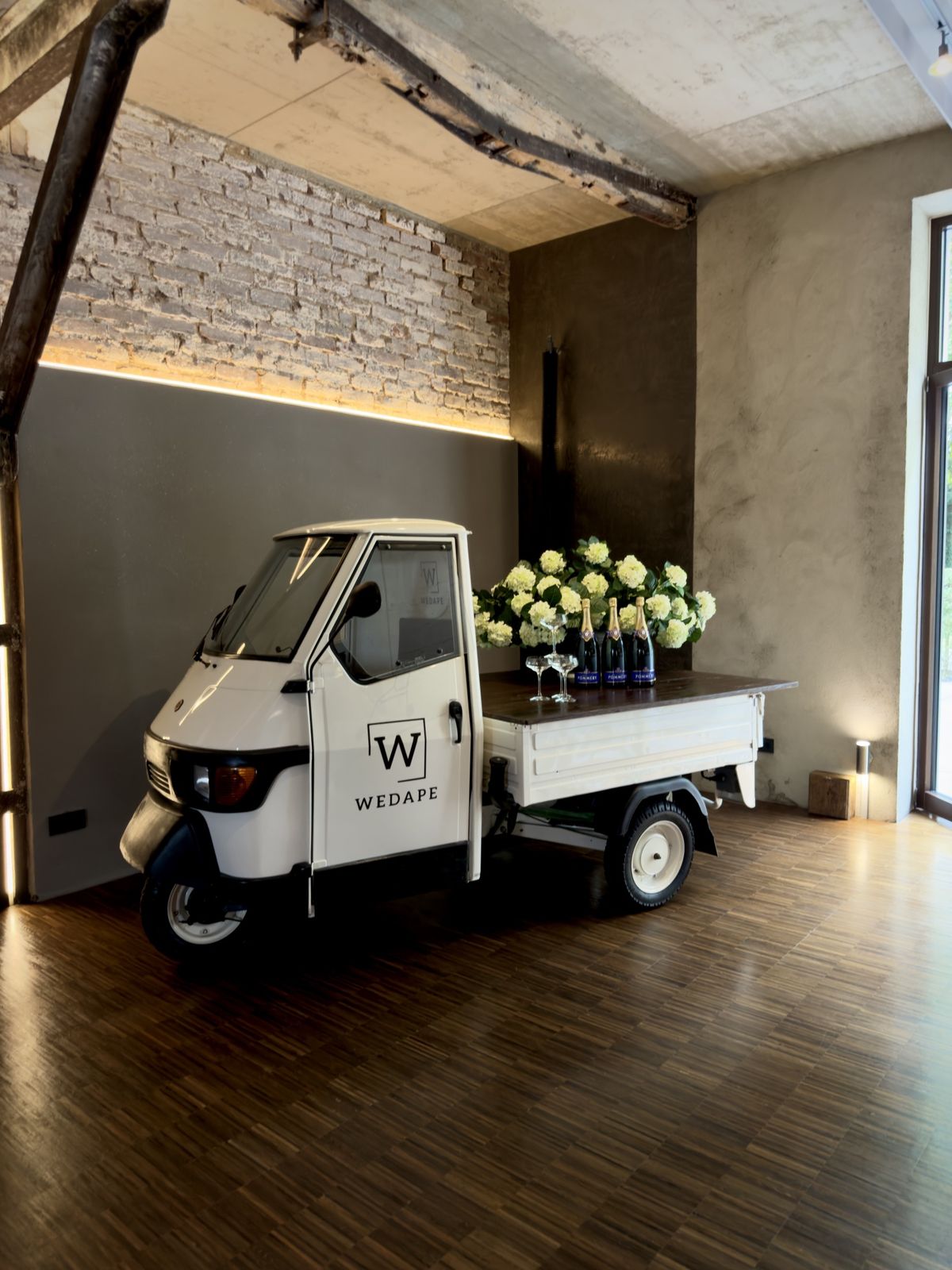 Piaggio Ape mit Sekt und Hortensien in einer Eventlocation