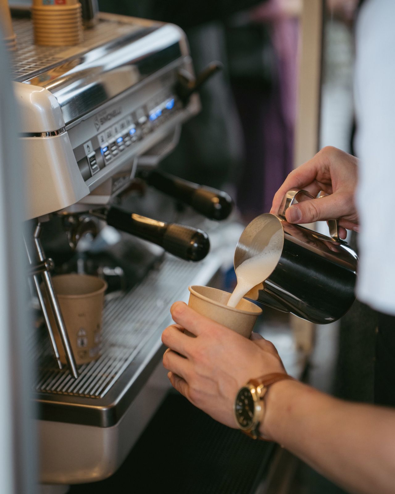 Milchschaum wird in einen Becher gegossen